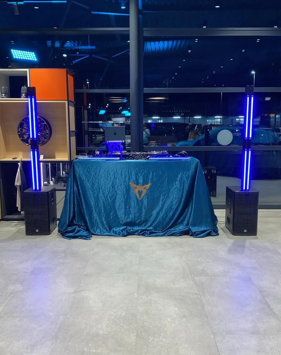 Aufgebautes DJ-Pult mit Lichtsäulen am Abend in der Halle eines Autohauses
