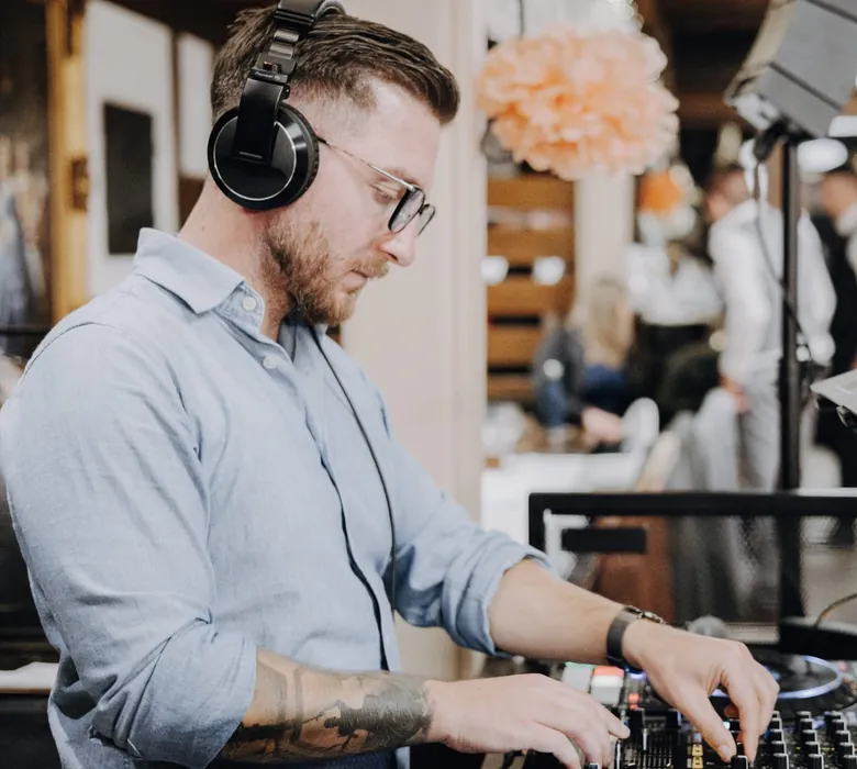 DJ mit Kopfhörer am Mischpult während einer Hochzeitsfeier