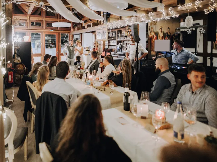 Rede am Mikrofon während des Dinners, der DJ steht am Pult im Hintergrund